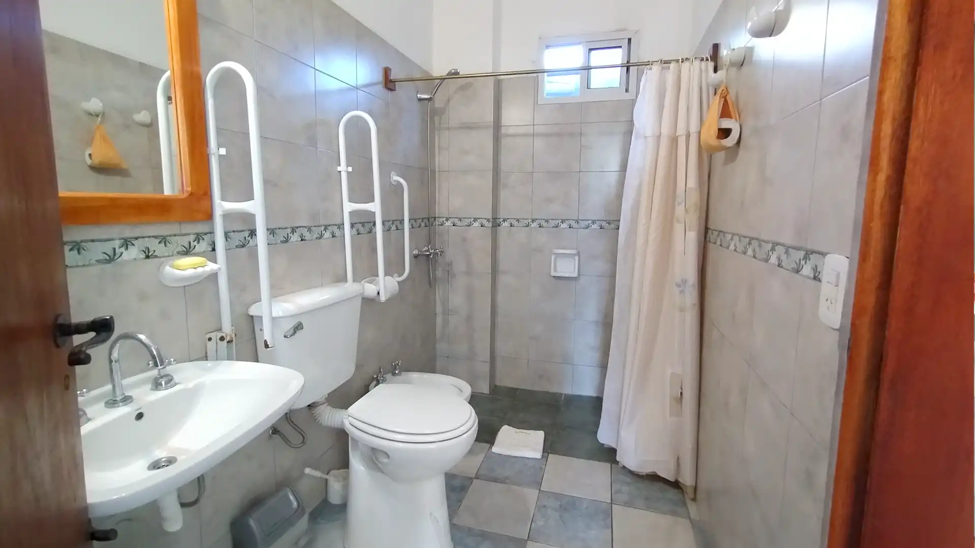 Baño adaptado con barrales y silla regulable para ducha